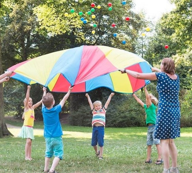 Participantes jugando con paracaídas, pelotas y globos